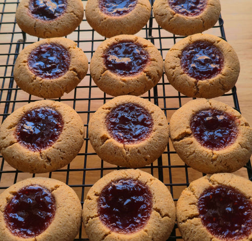 12 almond cookies with jelly filling on a cooling rack